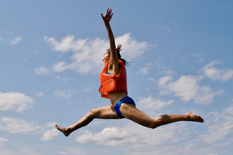 girl jumping off boat with life jacket on