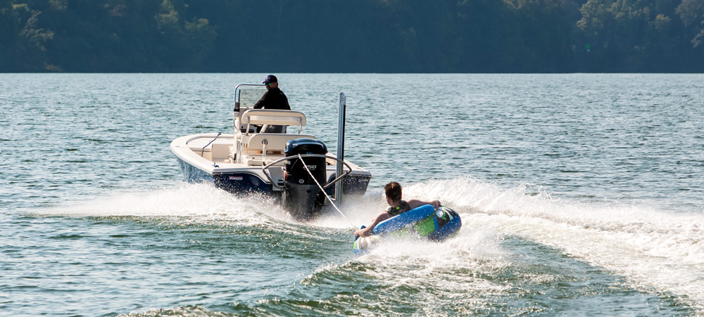 fishing boat pulling man on towable tube