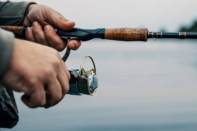 man's hand holding fishing rod and reel