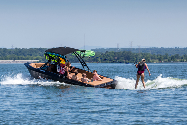 woman wakesurfing behind boat with wakeboard tower