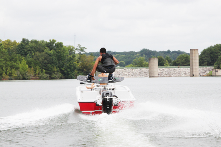 guy doing a wakeboard jump behind an outboard motor