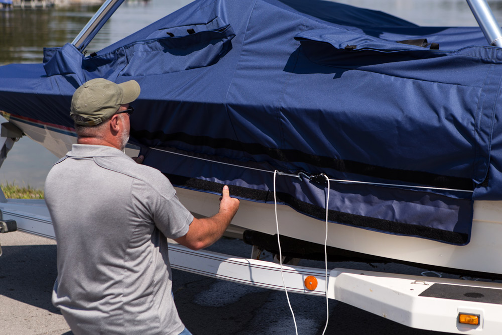 man tightening draw rope on boat cover